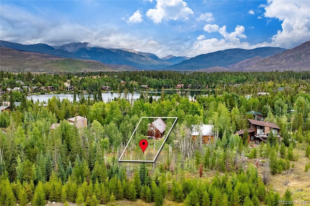 aerial view featuring a view of trees and a water and mountain view