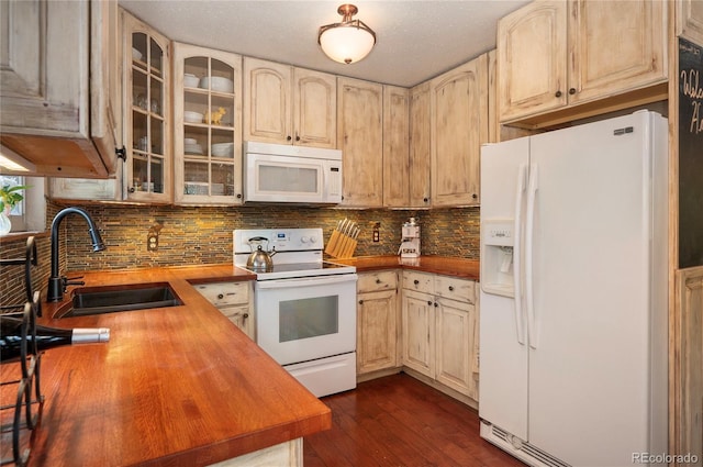 kitchen featuring white appliances, glass insert cabinets, tasteful backsplash, a sink, and butcher block countertops