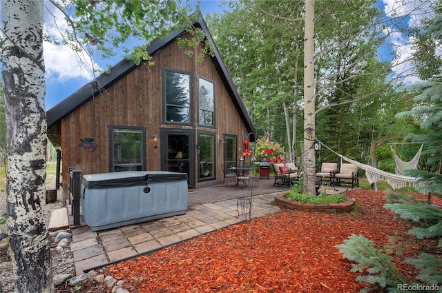 back of house with a patio area and a hot tub
