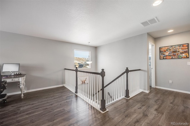 hallway featuring a textured ceiling and dark hardwood / wood-style flooring