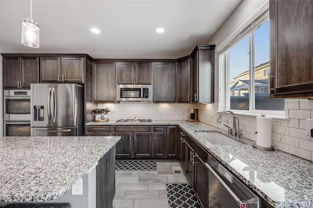 kitchen with stainless steel appliances, dark brown cabinetry, hanging light fixtures, and sink