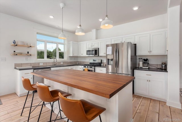 14051 US Highway 285, Salida, CO 81201 - kitchen with stainless steel appliances, wooden counters, white cabinetry, a kitchen breakfast bar, and recessed lighting