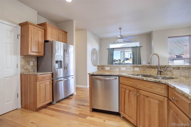 kitchen featuring light stone countertops, sink, ceiling fan, stainless steel appliances, and decorative backsplash