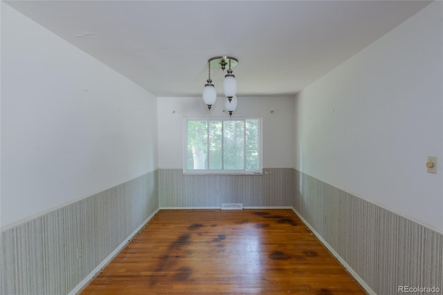 2976 S Magnolia Way, Denver, CO 80224 - unfurnished room with a wainscoted wall, wood finished floors, a chandelier, and wallpapered walls