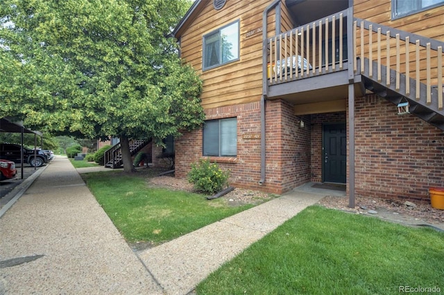 2237 S Buckley Rd Unit 101, Aurora, CO 80013 - view of side of home featuring stairs, brick siding, a yard, and a balcony