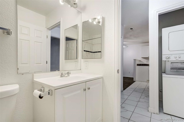 2237 S Buckley Rd Unit 101, Aurora, CO 80013 - bathroom featuring marble finish flooring, stacked washer / dryer, vanity, and a textured wall
