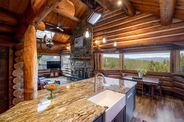 kitchen with high vaulted ceiling, a fireplace, dishwasher, sink, and dark wood-type flooring