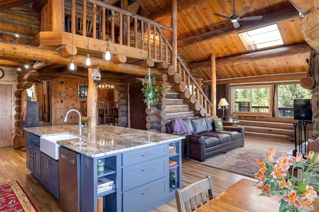 kitchen with sink, a kitchen island with sink, a skylight, high vaulted ceiling, and stainless steel dishwasher