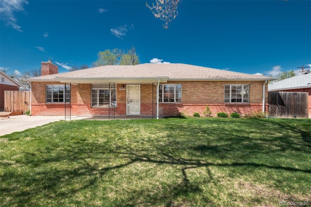 ranch-style house featuring fence, a chimney, a front yard, and brick siding