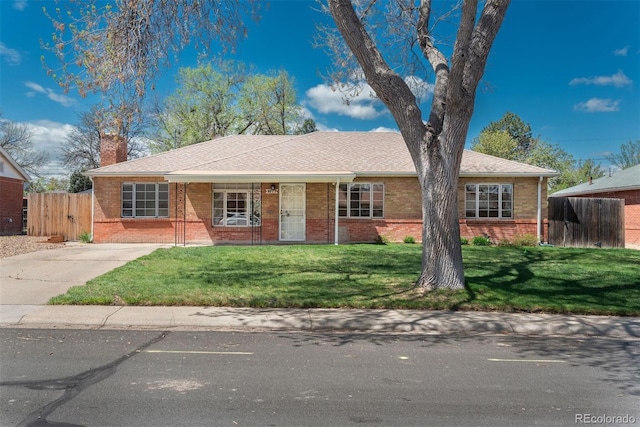 ranch-style house with fence, a chimney, a front yard, and brick siding