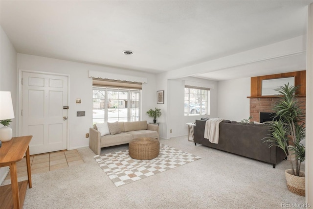 tiled living room featuring visible vents, a brick fireplace, and carpet floors