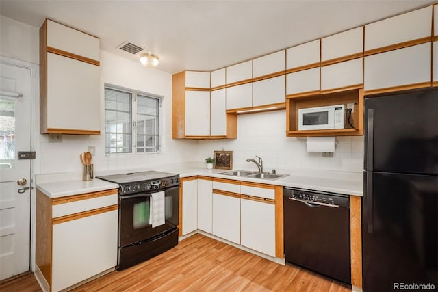 kitchen featuring a sink, light countertops, black appliances, and visible vents