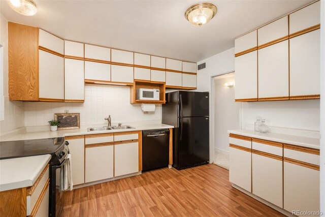 kitchen featuring visible vents, light wood-type flooring, light countertops, a sink, and black appliances