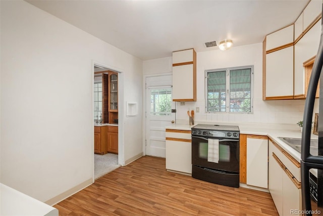 kitchen featuring visible vents, light wood-type flooring, light countertops, and black range with electric stovetop