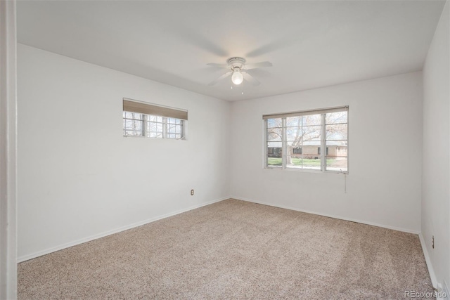 unfurnished room with a ceiling fan, baseboards, and carpet