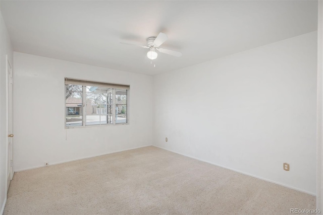 carpeted spare room featuring baseboards and a ceiling fan