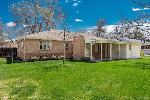 back of property featuring fence, a chimney, a lawn, and brick siding