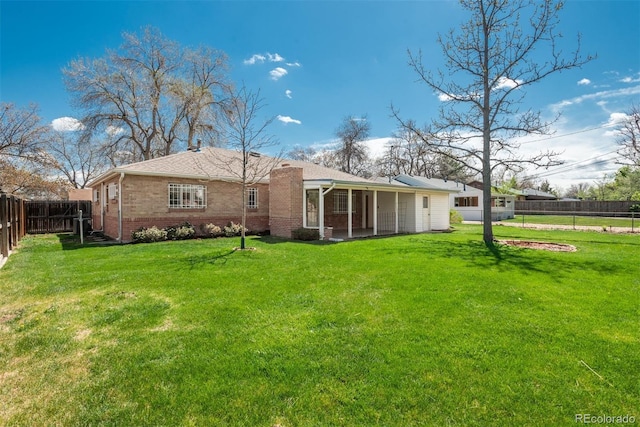 back of house with a yard, brick siding, and a fenced backyard