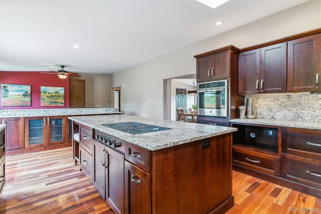 40192 Margaret Dr, Elizabeth, CO 80107 - kitchen featuring stainless steel oven, light wood-style flooring, a kitchen island, tasteful backsplash, and a ceiling fan