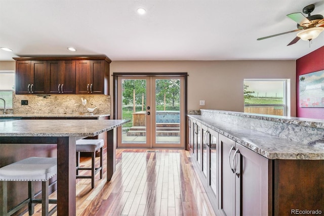 40192 Margaret Dr, Elizabeth, CO 80107 - kitchen featuring a kitchen breakfast bar, dark brown cabinetry, french doors, light wood-type flooring, and a ceiling fan