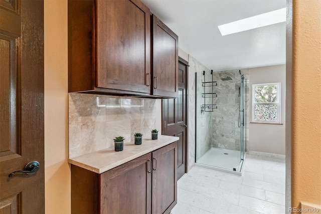40192 Margaret Dr, Elizabeth, CO 80107 - bathroom featuring a skylight, tasteful backsplash, a marble finish shower, and tile patterned floors