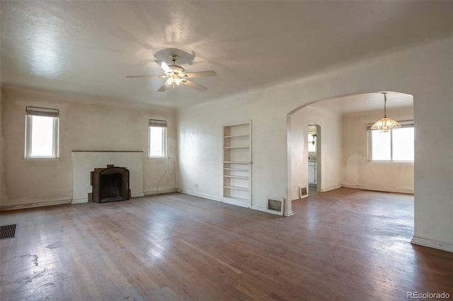 1335 Locust St, Denver, CO 80220 - unfurnished living room featuring arched walkways, healthy amount of natural light, ceiling fan, and built in shelves