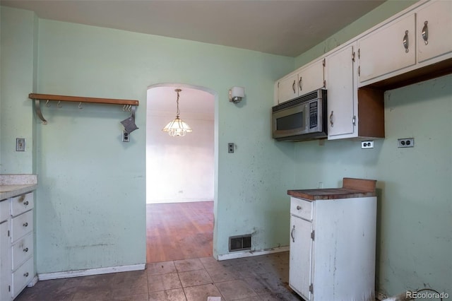 1335 Locust St, Denver, CO 80220 - kitchen with stainless steel microwave, white cabinetry, dark tile patterned flooring, and arched walkways