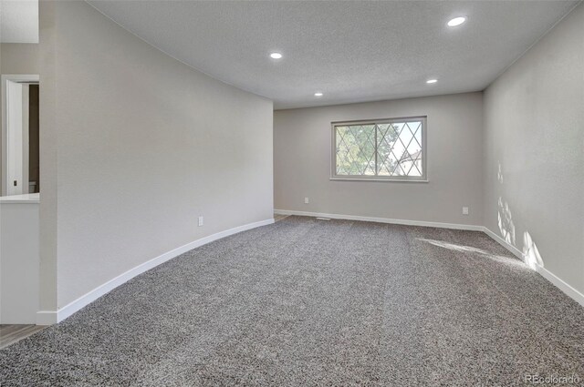 unfurnished room with a textured ceiling and carpet flooring