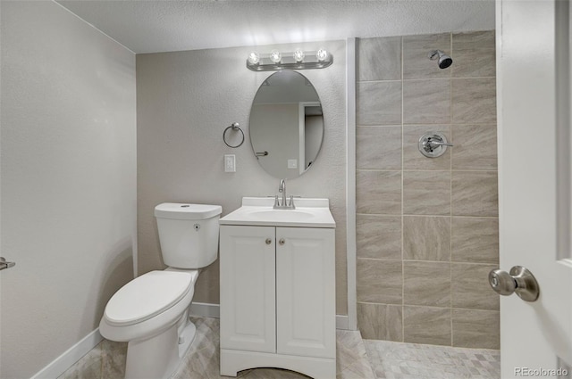 bathroom featuring vanity, toilet, and tiled shower