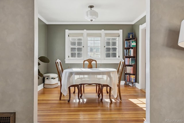 dining space with ornamental molding and light wood-type flooring