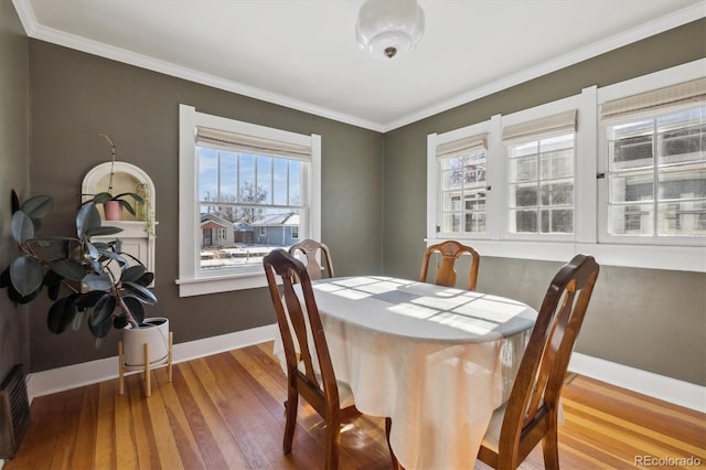 dining space with crown molding and wood-type flooring