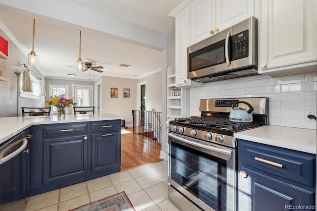 kitchen with blue cabinetry, ornamental molding, stainless steel appliances, and white cabinets