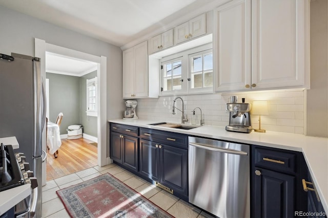 kitchen featuring sink, white cabinets, backsplash, light tile patterned floors, and stainless steel appliances