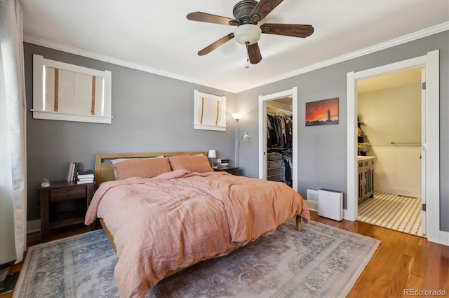 bedroom with ensuite bath, wood-type flooring, a spacious closet, a closet, and ceiling fan