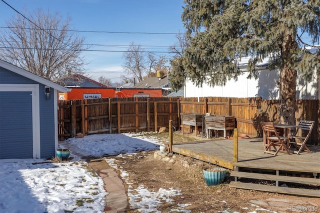 yard covered in snow featuring a wooden deck, a fenced backyard, and an outdoor structure