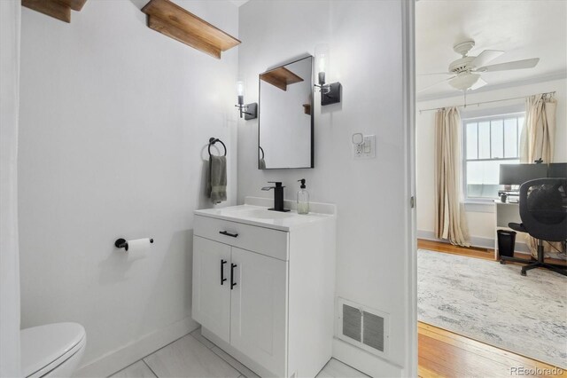 bathroom with visible vents, baseboards, toilet, vanity, and a ceiling fan