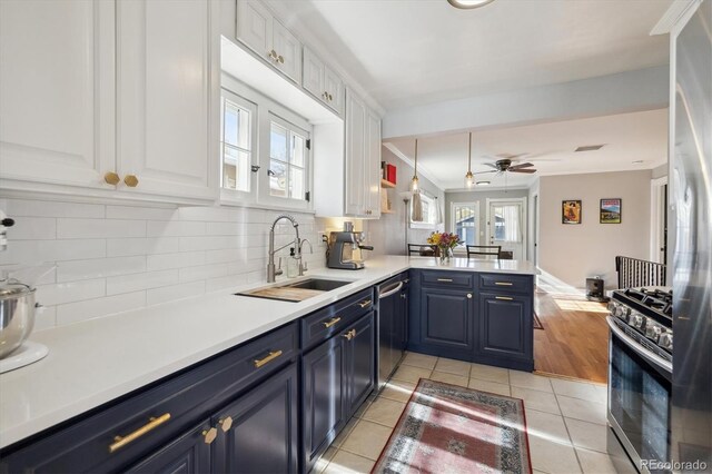 kitchen with a peninsula, white cabinets, stainless steel appliances, blue cabinets, and a sink