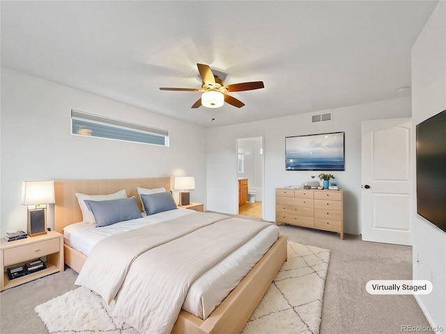 bedroom featuring light colored carpet, visible vents, ceiling fan, and ensuite bathroom