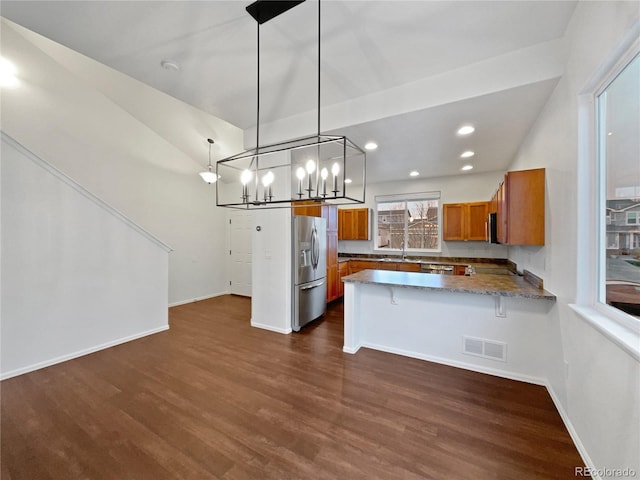 kitchen featuring a peninsula, visible vents, appliances with stainless steel finishes, brown cabinets, and dark wood finished floors