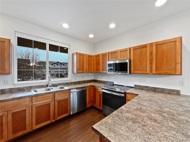 kitchen featuring brown cabinets, dark wood-style floors, stainless steel appliances, and a sink