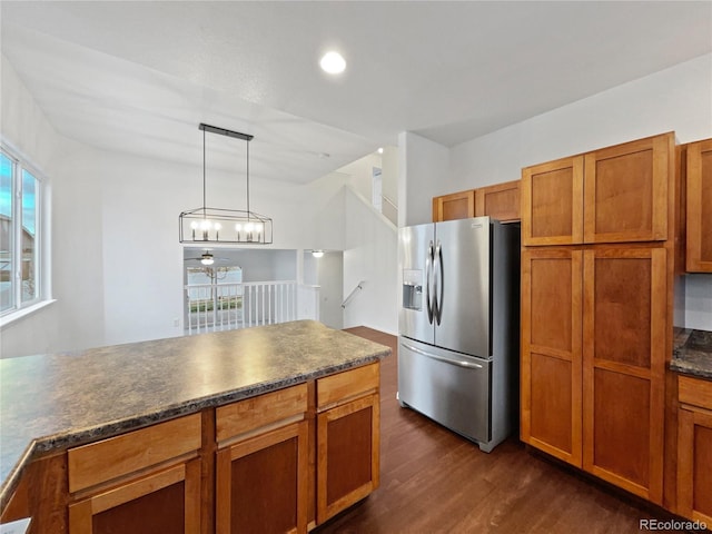 kitchen featuring dark wood-style flooring, dark countertops, brown cabinetry, a healthy amount of sunlight, and stainless steel fridge