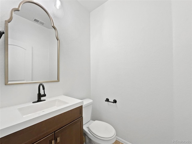 half bathroom with toilet, visible vents, and vanity