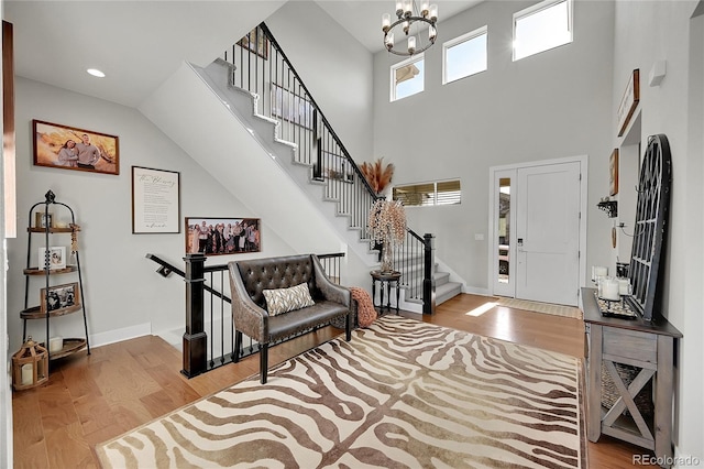 foyer with light wood-type flooring, a chandelier, and a high ceiling