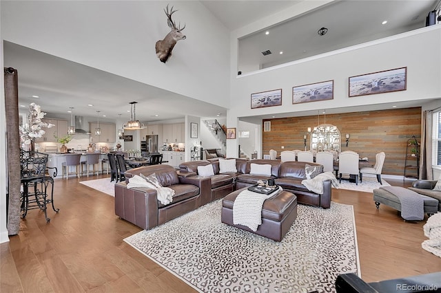 living room with a notable chandelier, wooden walls, and light hardwood / wood-style floors