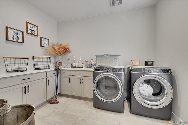 laundry room featuring light tile patterned flooring, cabinets, and washing machine and clothes dryer