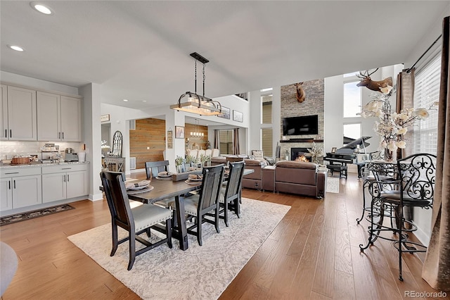 dining area with a stone fireplace and light wood-type flooring