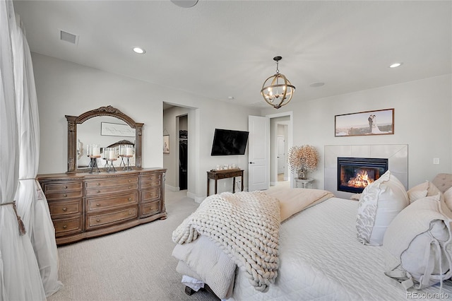 carpeted bedroom featuring a notable chandelier and a fireplace