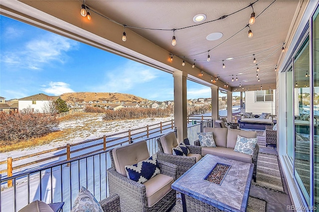 snow covered patio with a balcony, a mountain view, and an outdoor living space with a fire pit