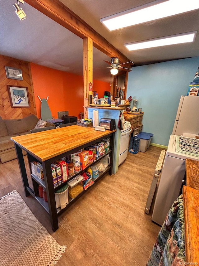 interior space with range, freestanding refrigerator, a ceiling fan, and wood finished floors