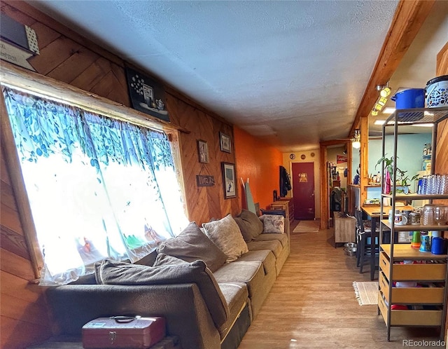 living area featuring a textured ceiling, wood finished floors, and wood walls